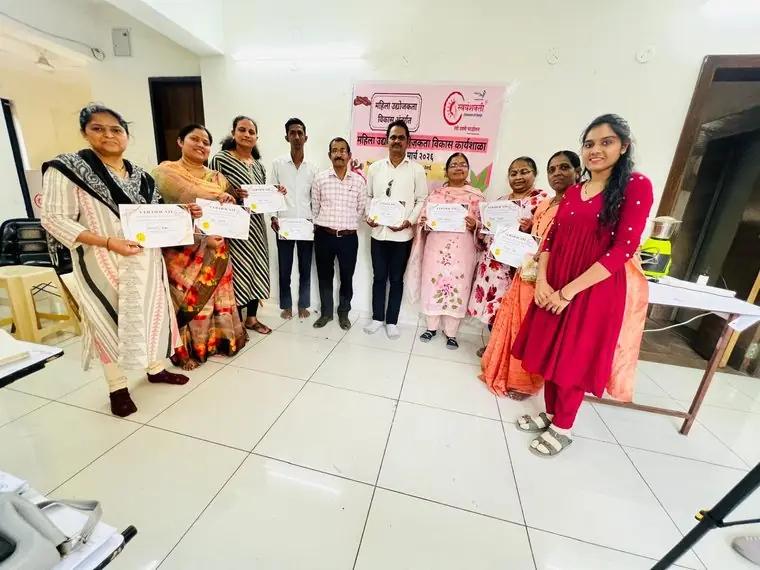 A group of people hold certificates in a bright room in front of the workshop banner